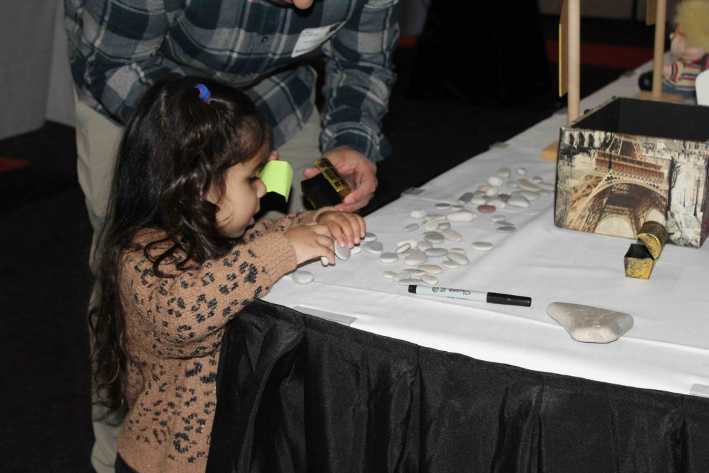 A child explores rocks on table to put in her treasure chest