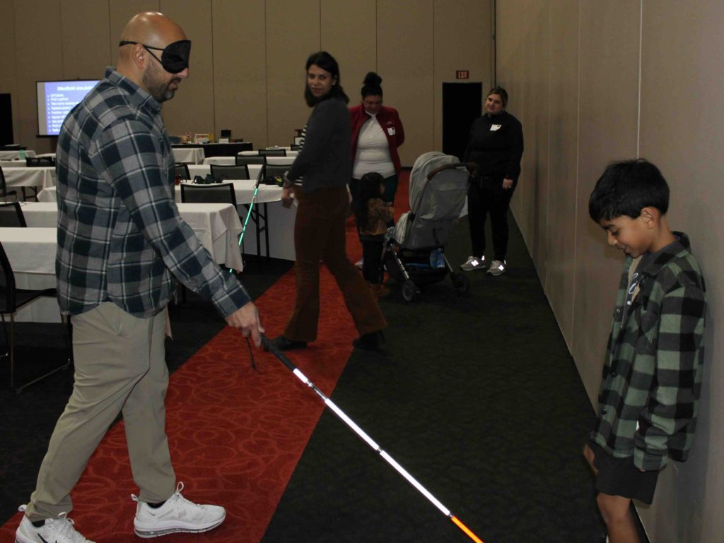 Father found his son with his cane as he is wearing a blindfold learning how to use a cane
