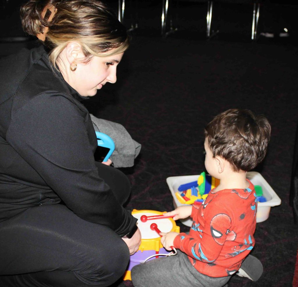 A mom on the floor playing a toy drum with her child